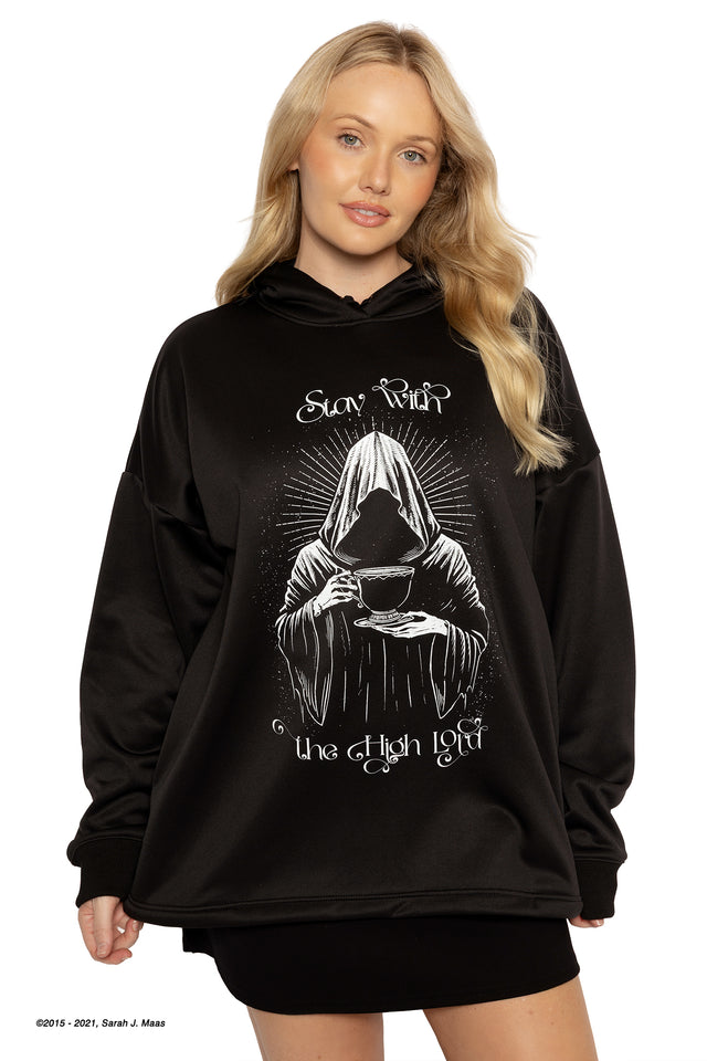 Model wearing a dark, textured hoodie with a structured silhouette, moving in soft light as the fabric catches detail, inspired by the mysterious, watchful presence of the Suriel in A Court of Thorns and Roses (ACOTAR).
